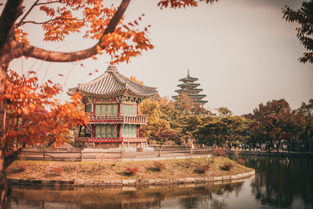 Traditional pavilion beside a pond at Gyeongbokgung Palace framed by colorful autumn leaves