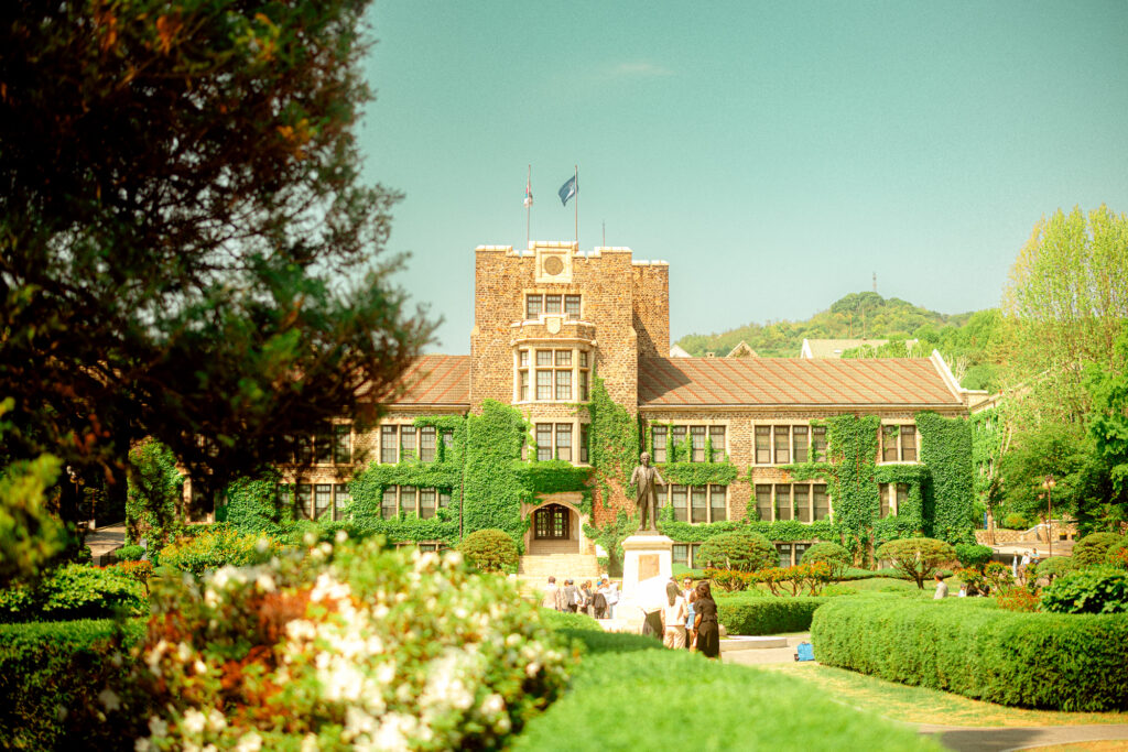 Ivy-covered stone university building and statue surrounded by landscaped gardens in Seoul