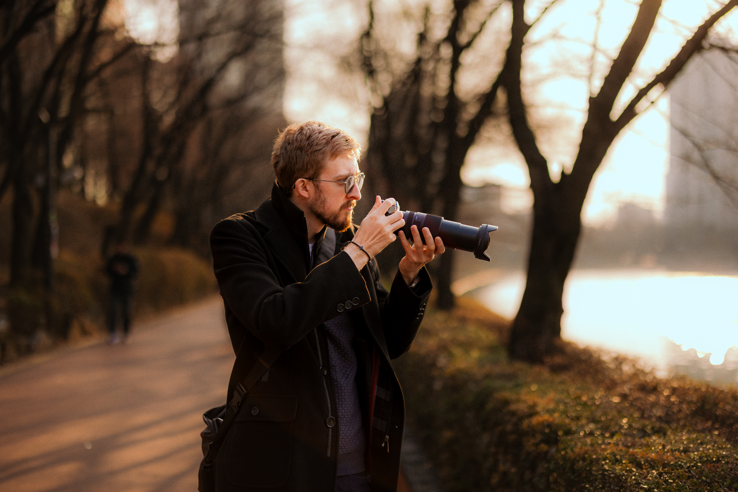 Photographer holding a camera with a telephoto lens in warm evening sunlight