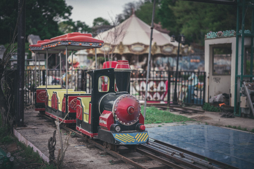 Red and black miniature train on narrow rails with a carousel behind it at Yongma Land.