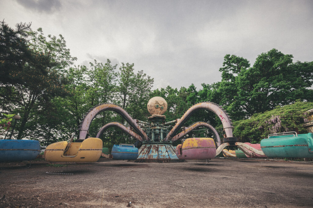 Weathered octopus ride with pastel seats beneath green trees at Yongma Land.